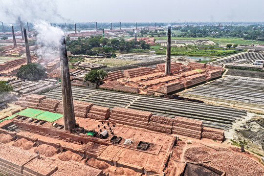 Aerial view of smoking brick kilns with vast stacks of red bricks under a hazy sky, Narayanganj, Dhaka Division, Bangladesh.