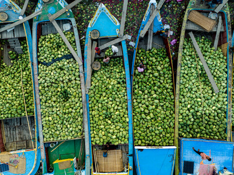Aerial view of boats brimming with green produce, a vibrant floating market scene unfolds with colorful vessels and bustling trade, Barishal, Barisal Division, Bangladesh.