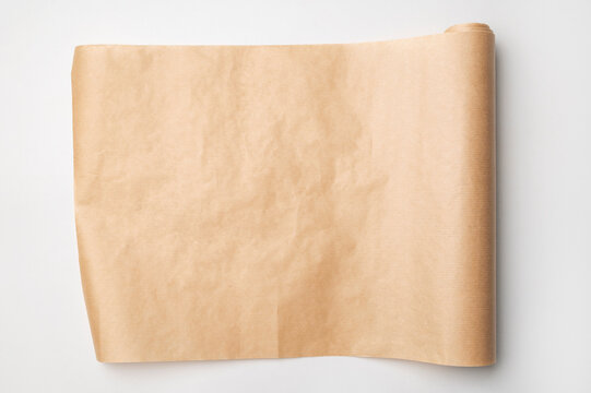An unrolled roll of baking paper on light gray background, top view. Brown parchment paper for cooking, baking bread or desserts. Space for text and inscriptions