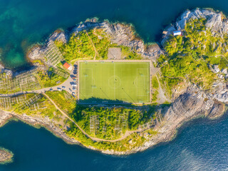 Aerial top down view of the famous Henningsvaer football stadium in Lofoten islands, Norway. Iconic soccer pitch on a rocky island surrounded by the sea. Scandinavian sports landmark from a drone. © biletskiyevgeniy