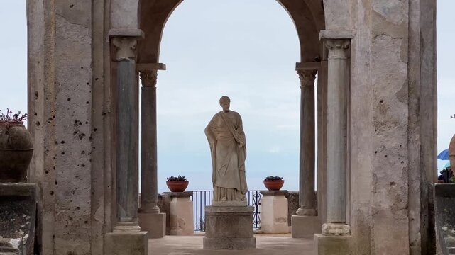 Statue of Ceres framed by classical arch at Villa Cimbrone in Ravello, Italy, overlooking the sea, elegant historic architecture and serene Mediterranean landscape.
