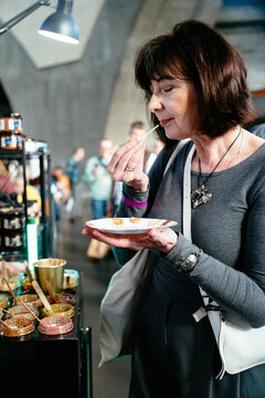Thoughtful brunette woman tasting peanut butter sample at craft market