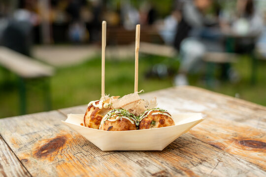 Takoyaki - traditional Japanese street food, outdoor snack with octopus Takoyaki fried balls