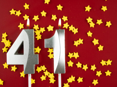 Concept of celebrating birthday and anniversary. Number 41 forty one silver celebration birthday candle on festive red Background. Forty one years birthday.