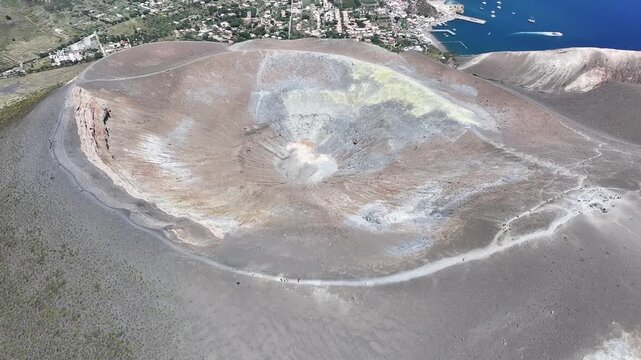 Aerial drone flying forward and descending directly into volcanic crater on Vulcano island showing dramatic terrain and geological formations.