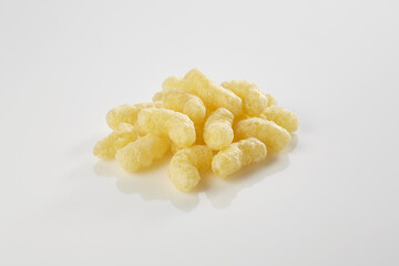 Yellow corn puffs snack pile on white background © EdienuFoto