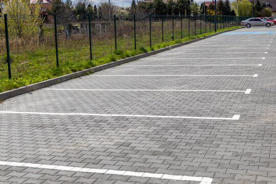 Empty Parking Lot With Marked Spaces and a Car in the Background on a Sunny Day in a Suburban Area