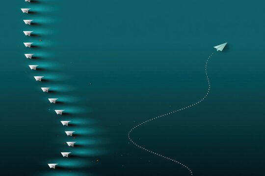 Single paper plane breaking formation over dark teal scene