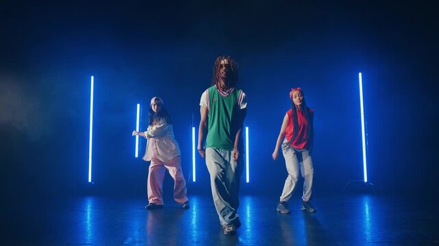 Group of hip hop dancer dancing together in a moody studio with tube neon lights.
