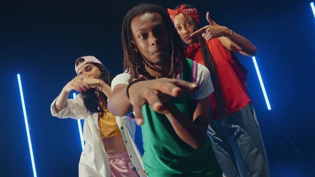 Group of hip hop dancer dancing together in a moody studio with tube neon lights.
