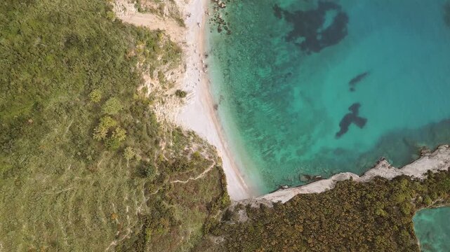 Aerial revealing view secluded non-commercialized Filikuri rocky beach.Clear turquoise Ionian sea meets steep rocky coastal cliffs. Scenic Albanian Riviera travel landscape in Himar&euml;, Albania.