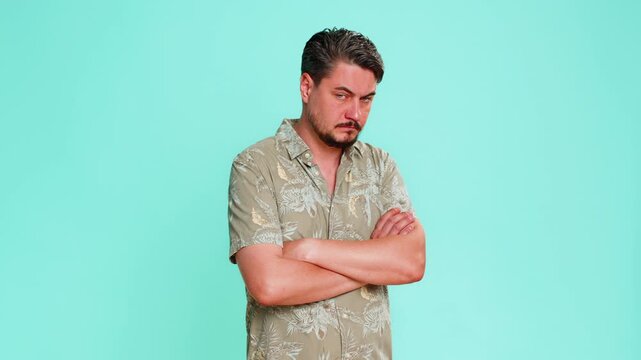 Middle-aged man squints eyes suspiciously, tilts head slightly, clearly showing mistrust, doubt towards someone or something. Young adult guy isolated on blue background displaying cautious attitude