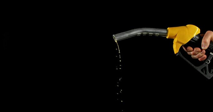 Super slow motion (1000 fps) fuel drops dripping from gasoline nozzle, symbol of depletion and fuel shortage. Minimal liquid flow on black background, dramatic lighting, energy crisis concept.