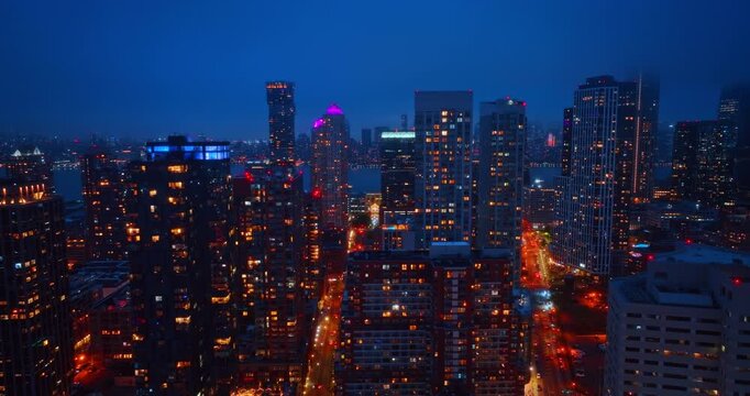 Moving slowly among the high-rises of downtown Jersey City, New Jersey, USA. Night city scenery from drone.