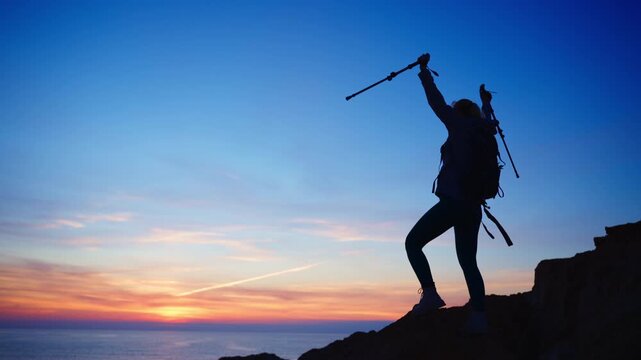 Female hiker silhouette standing on mountain summit at sunset, reflecting journey mindset while looking toward ocean horizon, symbolizing growth, freedom and new adventures ahead