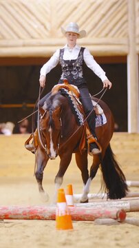 Cowgirl maneuvering horse around obstacles in arena in slow motion 4K