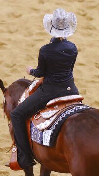 Cowgirl woman spin horse on rear legs at riding competition in slow motion