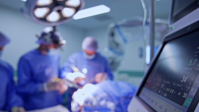 Footage near the screen of lung ventilating machine. Medical team works at operation in the blurred backdrop.