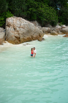 Couple kissing in tropical crystal clear water on paradisiac beach