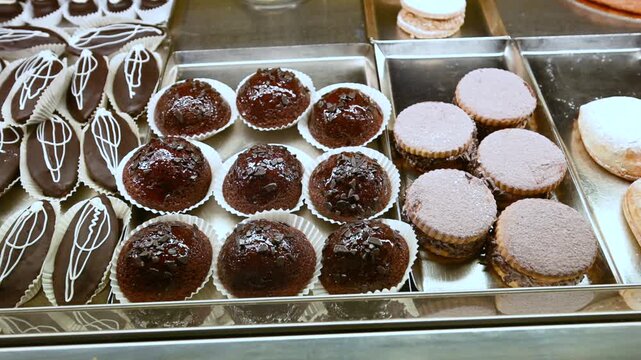 Assortment of fresh and delicious italian pastries and cakes displayed in a bakery shop window, including chocolate eclairs, rum babas, and other traditional sweets for breakfast