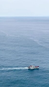 A white ferry carrying a crew and many cars sailing in the ocean on sunny day with clear skies. Indigo seawater with soft tone. Feeling fresh and relaxing. Ideas for holiday travel. Copy space on top.