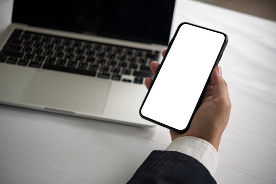 Top view hand holding smartphone blank screen mockup laptop desk professional suit business communication digital branding app development showcase marketing tools.