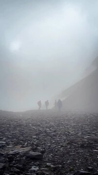The video shows a group of hikers walking through a foggy forest on the Wusun Ancient Road trek in Xinjiang Province, China. It's raining, and there's a layered view of mountains in the background.