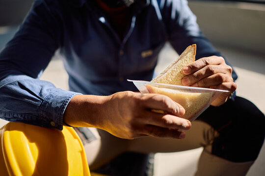 Close up of black worker eating sandwich at construction site.