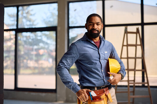 Smiling black worker at home renovation site looking at camera.