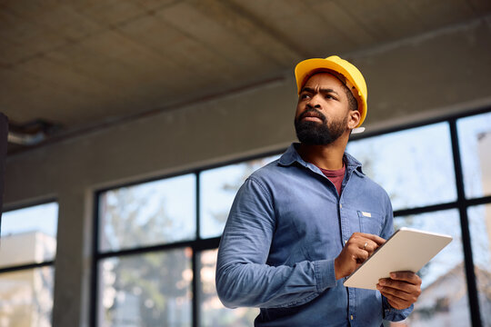 Black manual worker using touchpad while working on home remodeling project.