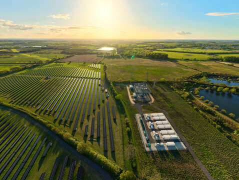 Aerial view of Tiln Photovoltaic Solar Farm and Battery Energy Storage System with rows of solar panels and storage units under a golden sunset Retford, England, United Kingdom.