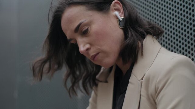 Upset Businesswoman Putting in a Wireless Earbud Outdoors