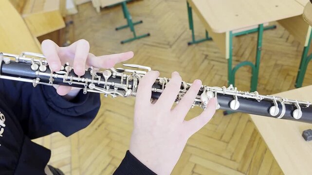 Close up of hands playing oboe in music school.