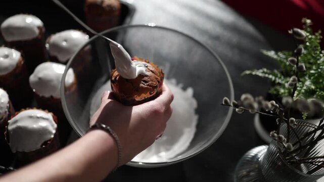close up hand spreading icing on easter paska soft white cream covering bread festive baking moment traditional dessert preparation homemade kitchen scene