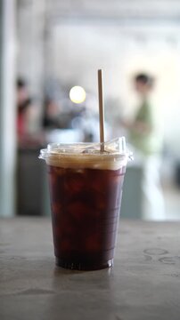 inematic close-up of white wireless earbuds on a laptop keyboard with a glass of iced coffee in a blurred background, modern remote workspace and cafe lifestyle concept