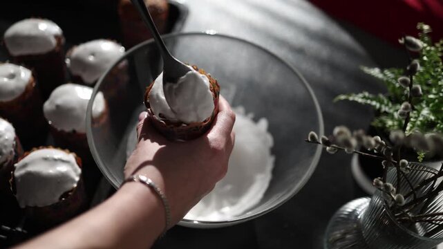 close up slow motion spreading white icing over easter paska soft creamy texture traditional holiday baking process homemade sweet bread decoration