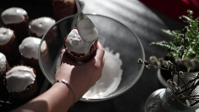 close up baking process traditional easter bread paska being covered with white icing smooth spreading texture festive homemade dessert preparation