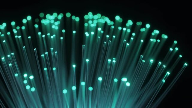Close-up of Fiber Optic Cables Emitting Green Light on a Dark Background.