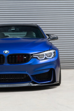 Blue BMW M4 led headlight close up, Premium sports car front end detail in front of metal wall