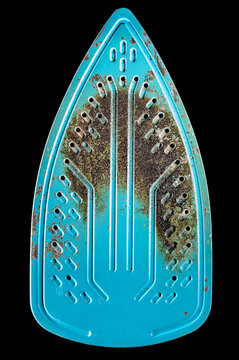 Close-up of a heavily rusted and worn turquoise iron soleplate with steam holes