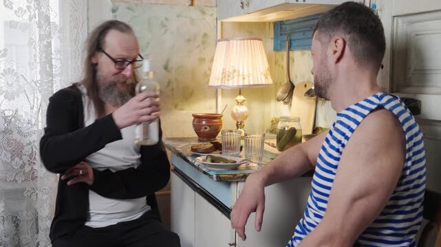 Two men alcoholics drinking Russian vodka sitting on the kitchen with 1990 style interior