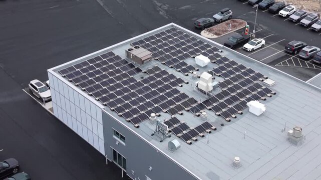 aerial view of a large rooftop solar array on an auto dealership building in Halifax, Nova Scotia. Modern grid-tied photovoltaic system with mounting racks and inverters for distributed energy 4K.