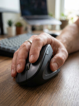 Ergonomic vertical mouse being used by a hand on a desk