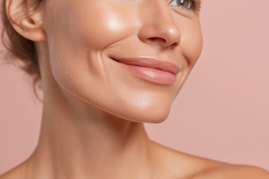 Glowing cheek soft smile close up female face smooth skin pink background natural makeup dimples healthy skin