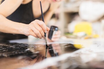 Obraz premium A skilled artisan carefully applies gold foil to a glass surface, creating stunning artwork that enhances luxury furniture and decorations with a rich, exquisite finish