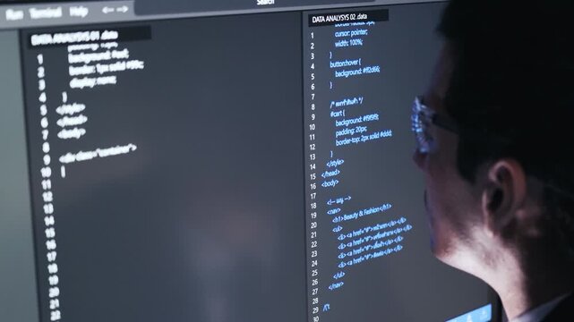 Programmer wearing glasses coding on dual monitors, editing HTML and CSS on a dark-themed interface