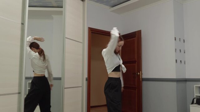 Young woman in casual clothes performs contemporary dance in her bedroom. Energetic and graceful female dancer practicing moves at home, expressing herself through movement with passion and skill