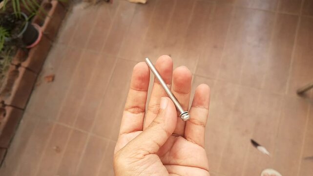 A close up shot of a hand holding and showing a long, heavily rusted iron hex head bolt from an old tool collection.