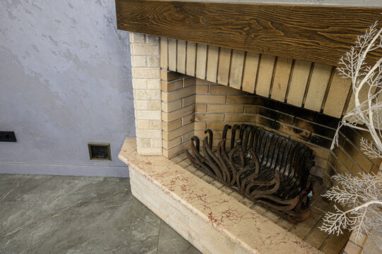 Brick fireplace with dark wooden mantel, marble-like hearth, ornate cast iron grate, textured grey walls, decorative white branches, rustic yet elegant design