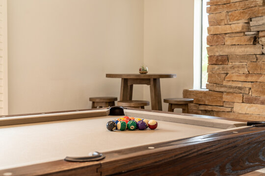 Close-up pool table with racked balls and wooden bar stools and table